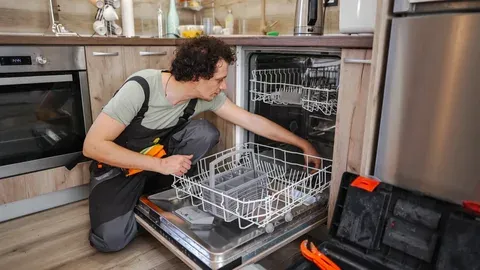 Skilled repairman checking the racks and internal components of a built-in kitchen dishwasher.