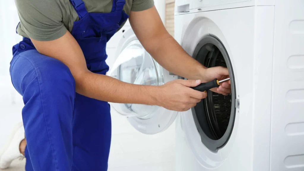 Close-up of a technician using a screwdriver to fix the internal drum of a white washing machine.