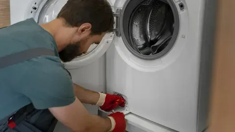 Repair expert wearing protective gloves removing and cleaning the drain filter of a washing machine.